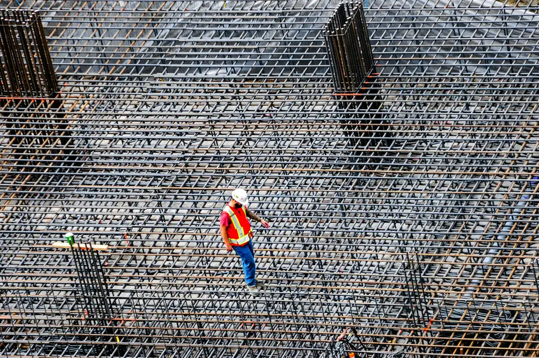 Construction worker inspecting a rebar grid before a concrete pour